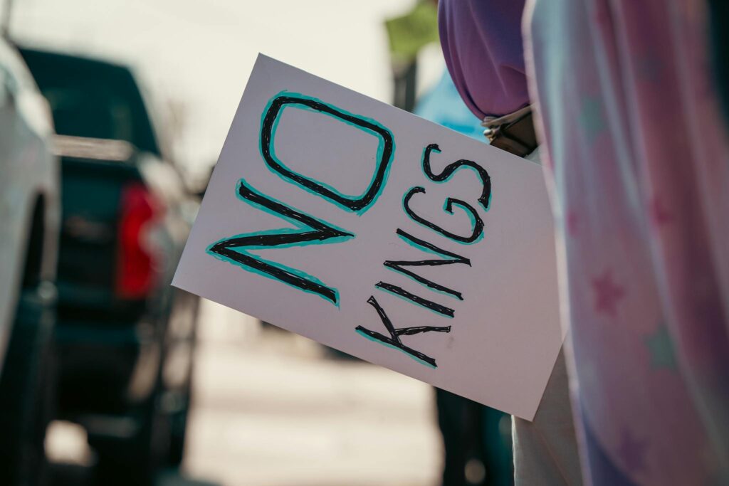 Protester holds a sign with 'No Kings' message during street demonstration.